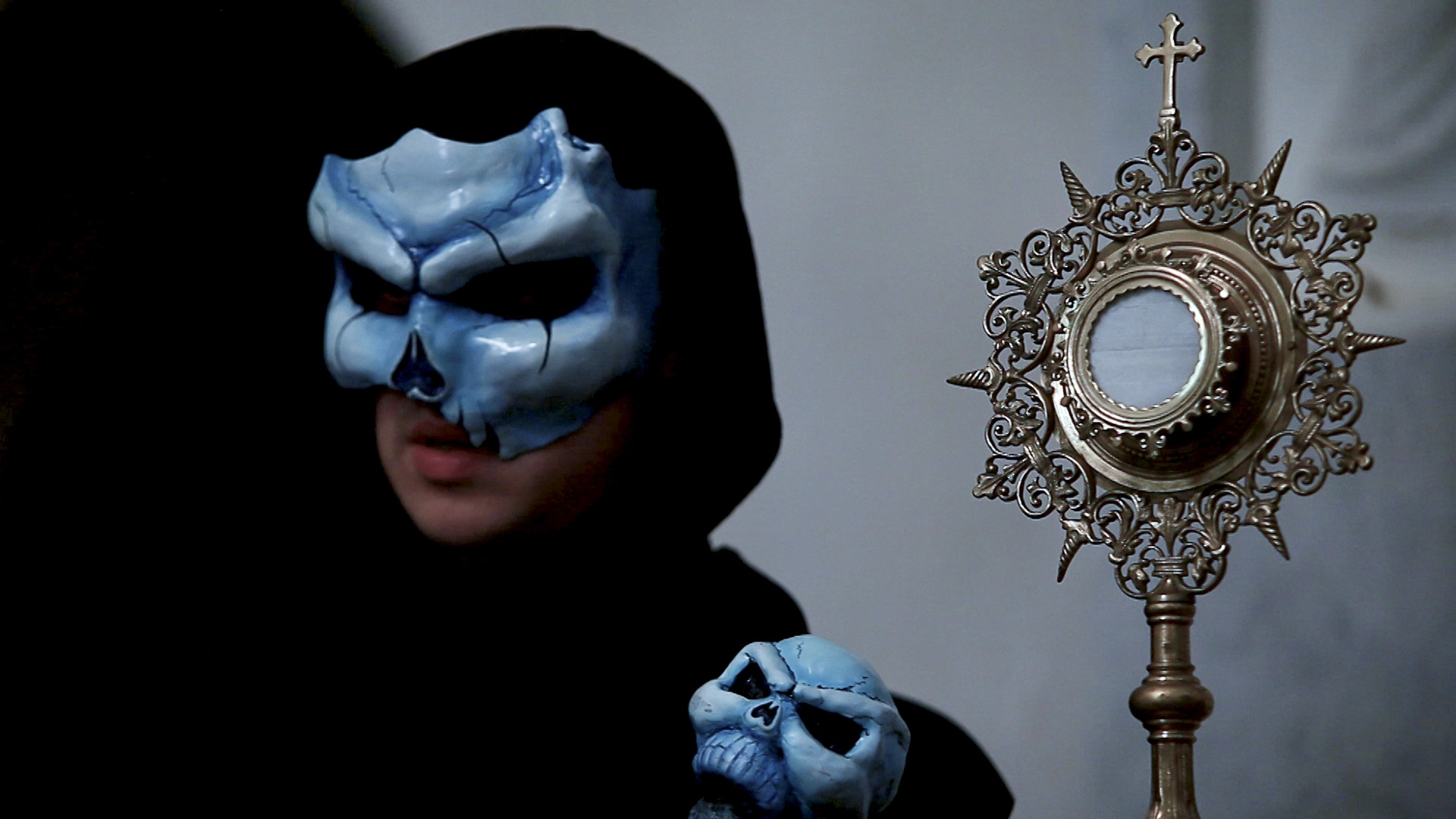 A skull-masked spirit beside an ornate monstrance